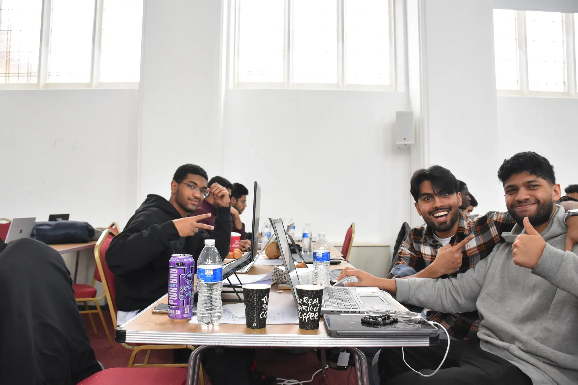 Hackathon participants smiling and giving thumbs up at their table