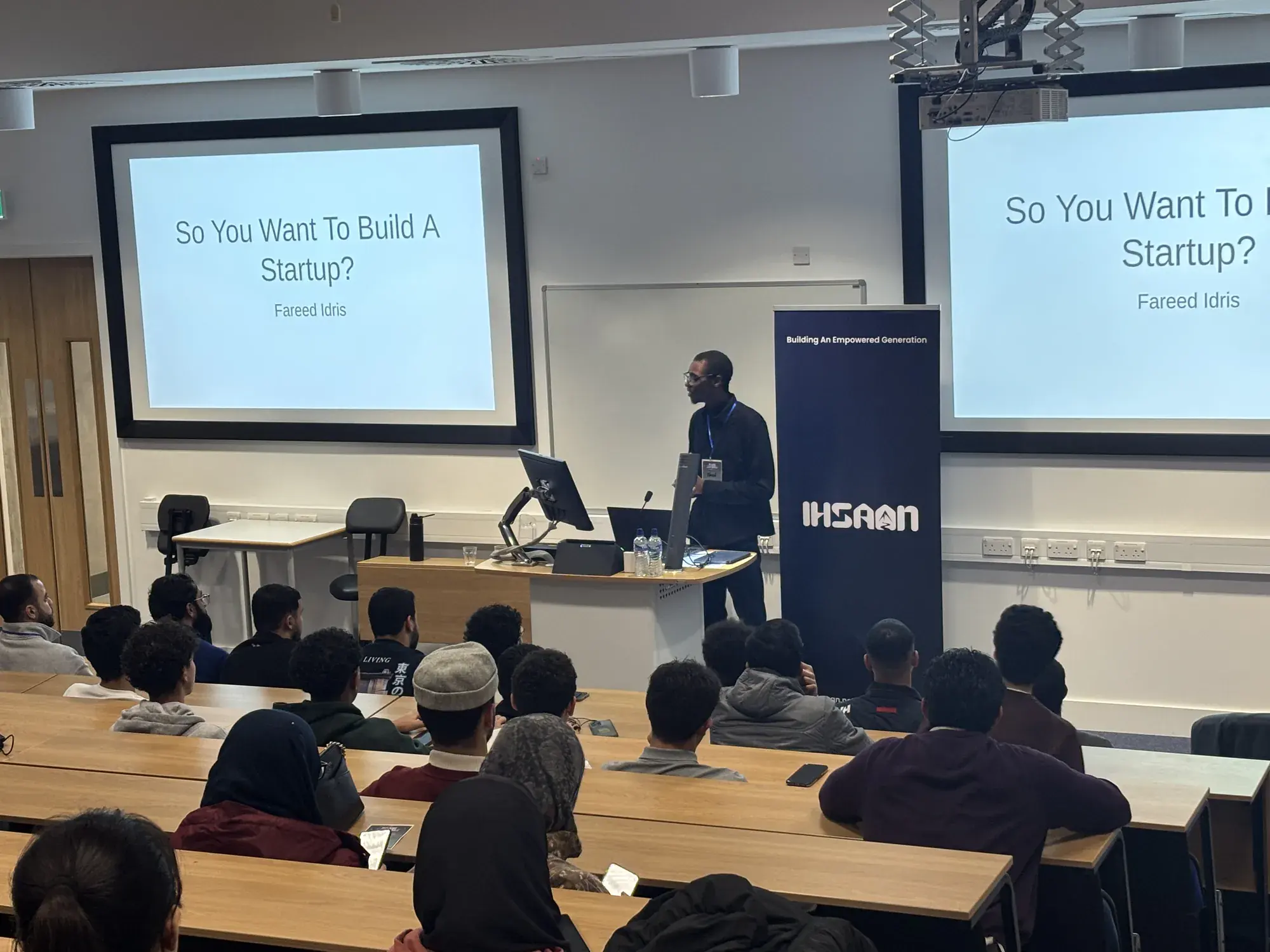 A speaker presenting a startup talk beside an IHSAAN banner